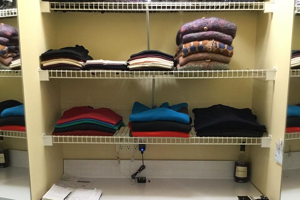 Neatly folded and color-sorted sweaters on closet wire shelving