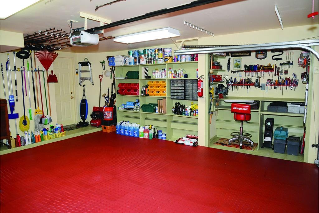 Fully organized garage with red flooring, wall storage, and tool shelving