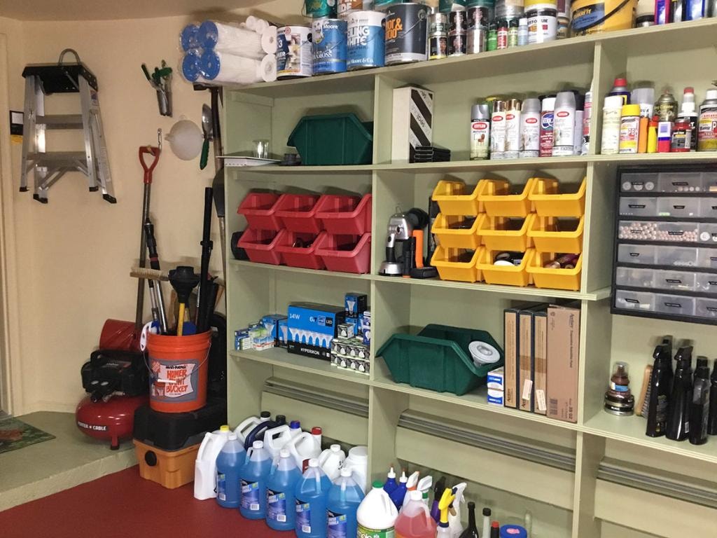 Closeup of organized garage shelving with bins, paint cans, and supplies