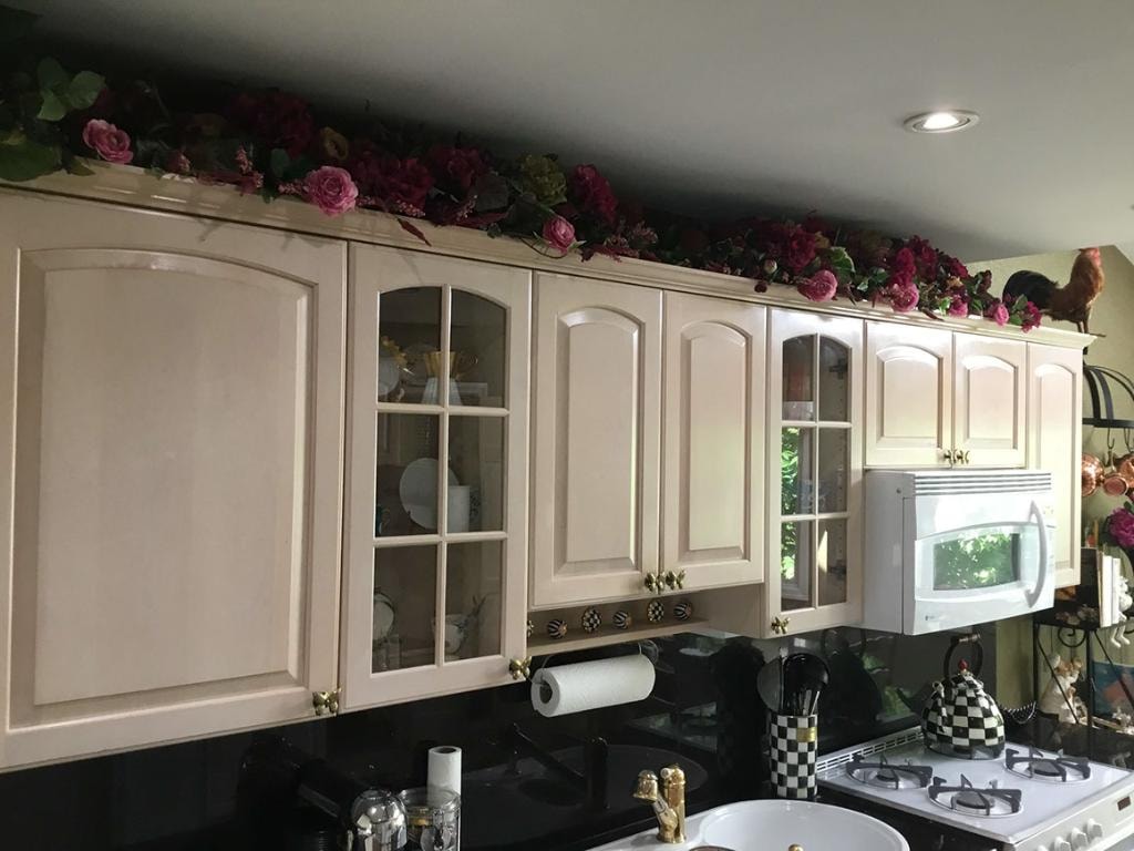 Kitchen with cream cabinetry and floral arrangement above cabinets