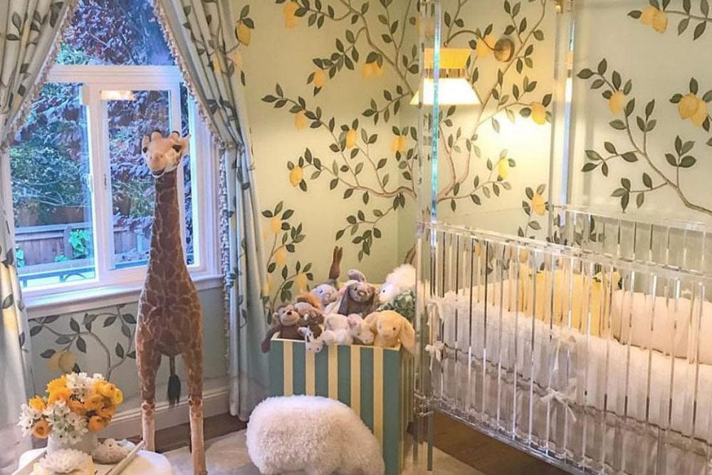 Charming nursery with lemon botanical wallpaper, acrylic crib, and giraffe plush
